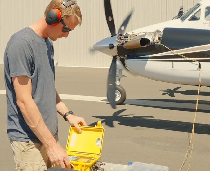 Technician running a ground test beside a King Air propeller